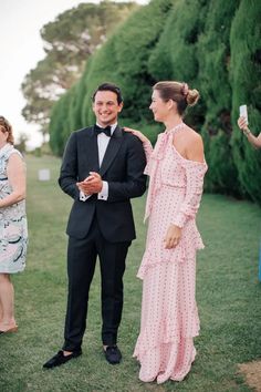 a man in a tuxedo standing next to a woman in a pink dress