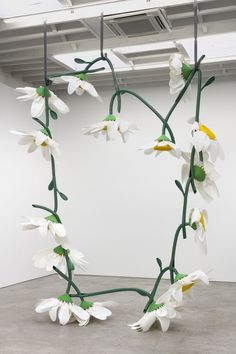 a sculpture with white flowers hanging from it's sides