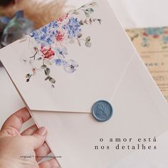 a person holding an envelope with flowers on it and a wax seal in their hand