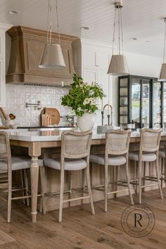 a large kitchen with wooden floors and an island in the middle, surrounded by white cabinets