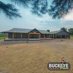 a large house sitting in the middle of a dirt field next to a pine tree