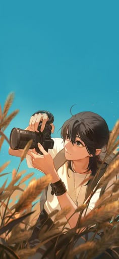 a person holding a camera in front of some tall grass