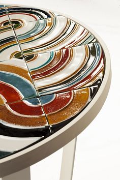 an artisticly designed table with colorful circles on it's surface and white legs