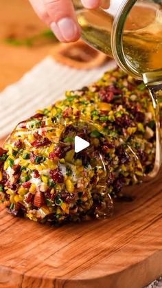 someone is pouring something into a glass on a cutting board with other food in it