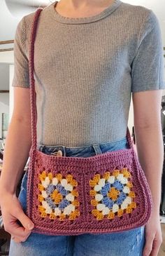 a woman is holding a crocheted purse