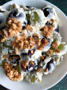 a white plate topped with grapes and ice cream covered in toppings on top of a green table