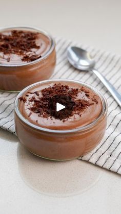 two desserts are sitting on a table with spoons