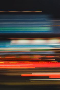 blurry photograph of an orange and blue train passing by in the night time sky