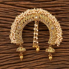 a brooch with pearls and bells hanging from it's side on a wooden surface