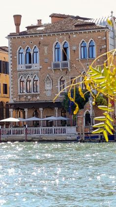 an old building on the side of a river next to buildings with balconies