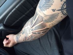 a man's arm with a clock and wings tattoo on his left arm, sitting in a car