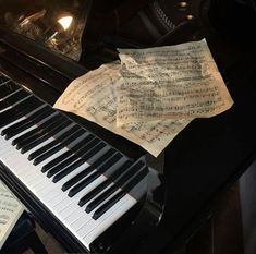 an old piano with sheet music sitting on it's side next to the keyboard