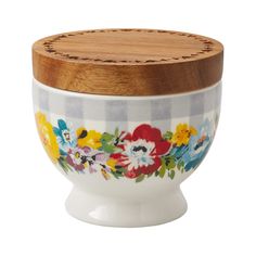 a white bowl with flowers painted on it and a wooden lid sitting on a stand