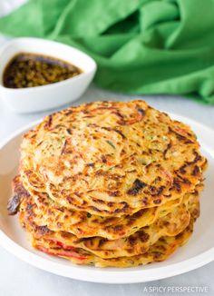 a stack of food on a white plate next to a bowl of chili and green beans