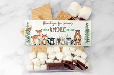 an assortment of marshmallows and chocolate on a white marble counter with a thank you for coming sign