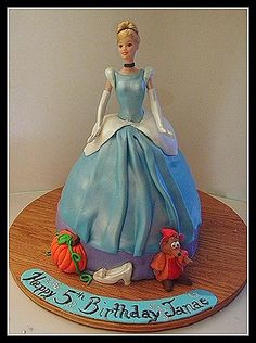 there is a cake that looks like a woman in a blue dress on top of a table