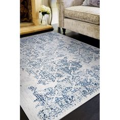 a blue and white area rug with an ornate design on the floor in front of a couch