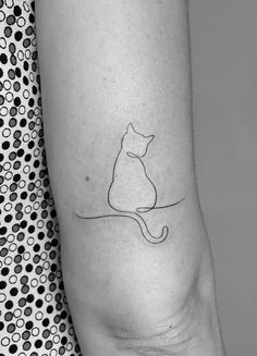 a black and white photo of a cat tattoo on the left arm, with dots in the background