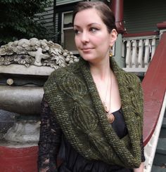 a woman standing in front of a fountain wearing a green shawl and black dress