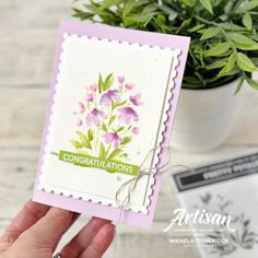 a hand holding up a card with flowers on it and the words congratulations written in green ink