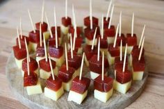 small appetizers with toothpicks are arranged on a wooden platter