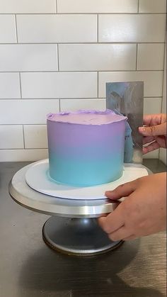 a person is decorating a cake with purple and blue frosting