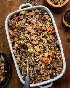 a casserole dish filled with wild rice, cranberries, and nuts