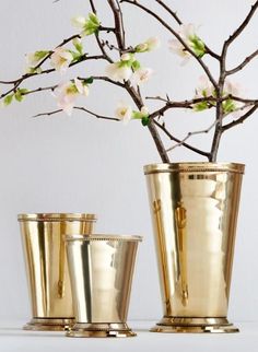 three gold cups with flowers in them sitting on a table