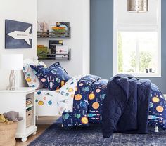 a child's bedroom with blue walls and space themed bedding