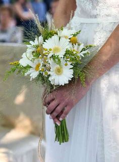 a bride holding a bouquet of white and yellow flowers