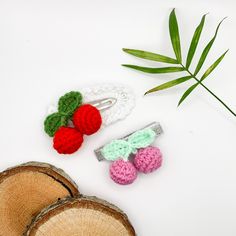 three crocheted hair clips sitting on top of a white table next to a green plant