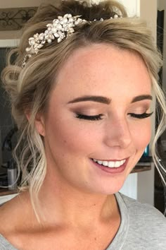 a woman with blonde hair wearing a tiara and smiling at the camera while looking down