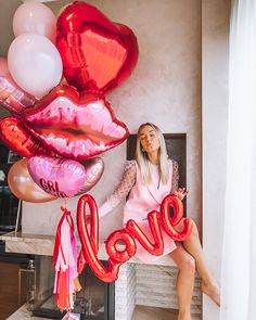 a woman sitting on a chair with balloons in the shape of lips and word love