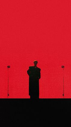 the silhouette of a man standing in front of two microphones on a red background