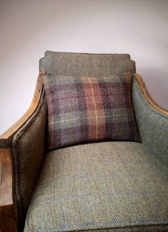 an old chair with a plaid pillow on it's back and armrests