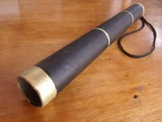 an old telescope on a wooden table with a cord attached to the end of it