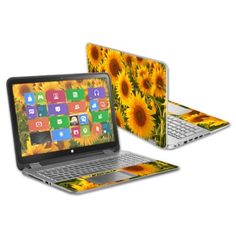 an open laptop computer sitting on top of a white surface with sunflowers in the background