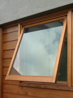 an open window on the side of a building with wooden siding and shingled windows