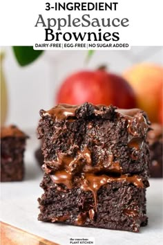 three brownies stacked on top of each other with chocolate drizzle and apples in the background