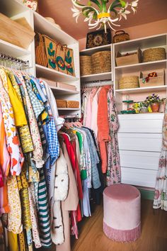 an organized closet with clothes, shoes and other items on shelves in front of a chandelier