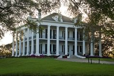 a large white house sitting on top of a lush green field