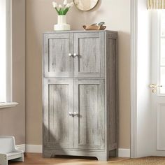 a tall wooden cabinet sitting next to a window in a room with beige walls and hardwood floors