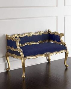 a gold and blue couch sitting on top of a wooden floor next to a white wall