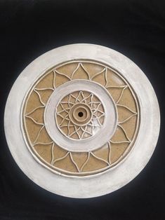 a white and brown circular object on a black surface with an intricate design in the center