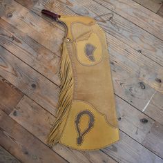 a brown leather case with an embroidered design on the side and fringes around it