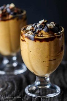 two glasses filled with dessert sitting on top of a table