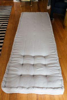 a mattress is laying on the floor in front of a black and white striped rug