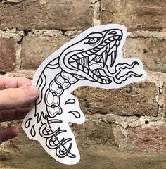 a hand holding up a sticker with an image of a lizard in the middle