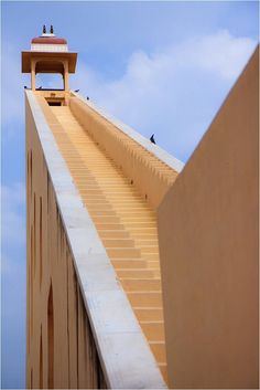 birds are sitting on the top of a tall building with steps leading up to it