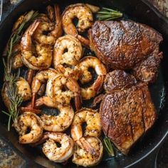 steak and shrimp in a cast iron skillet with rosemary garnish on the side